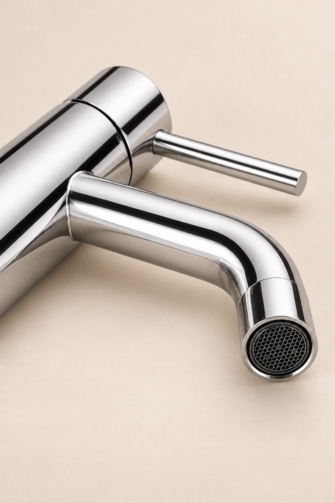Mitigeur lavabo bas design Mireva chromé Azéo — gros plan en plongée sur le bec chromé poli, l'aérateur nid d'abeille et le levier