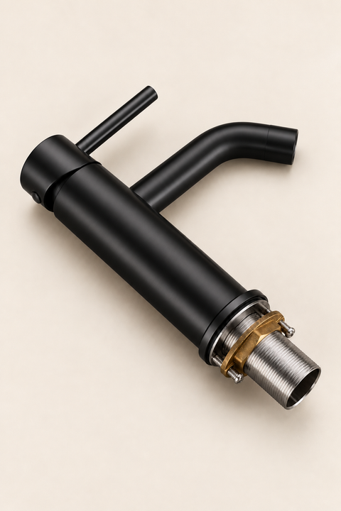 Mitigeur lavabo bas design Mireva noir mat Azéo — mitigeur allongé à plat sur fond crème, vu en plongée, avec sa tige filetée et l'écrou de fixation en laiton