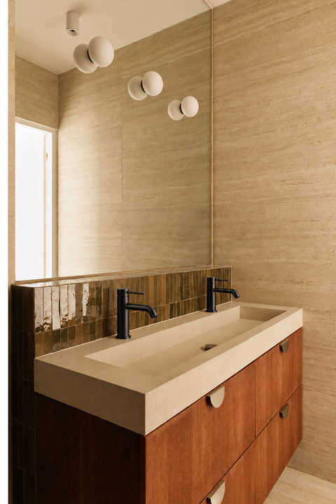 Mitigeur lavabo bas design Mireva noir mat Azéo — deux mitigeurs sur une vasque double en pierre beige, meuble en bois rouge et crédence en zellige vert