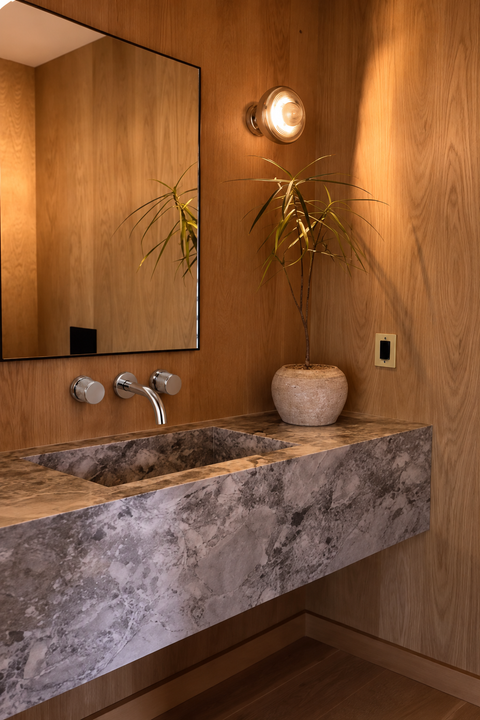 Mitigeur lavabo mural encastré double poignée Havren chromé Azéo — au-dessus d'une vasque monobloc en marbre gris veiné, murs en lambris de bois et miroir noir